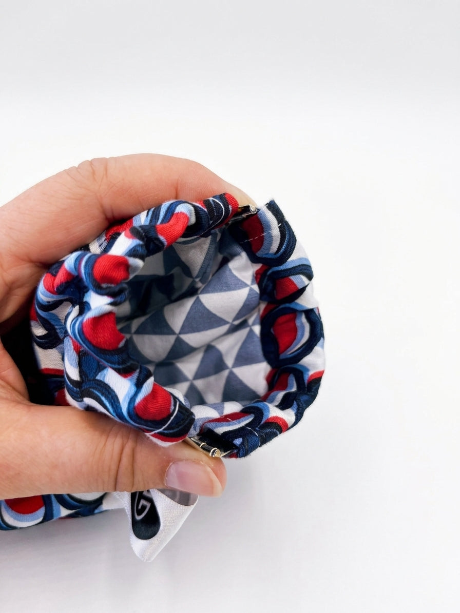 Detailansicht des Brillenetuis ELOISE mit geometrischem Innenfutter in Grau, Weiß und Dunkelblau sowie rot-blau-weiß gemustertem Baumwollstoff und Klappverschluss.
