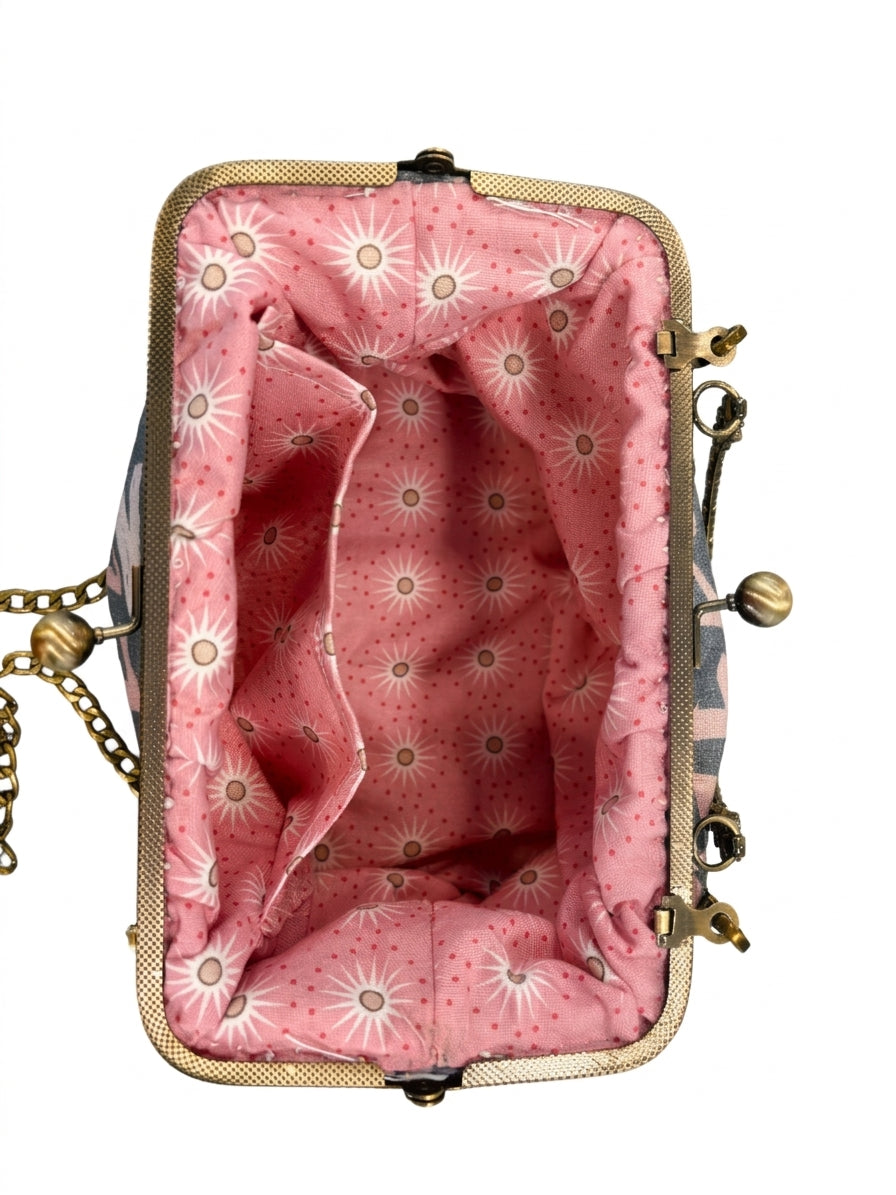 Innenansicht der Bügeltasche LOVE LETTER mit rosafarbenem Futter, weißem Sonnenblumenmuster und antikgoldfarbenem Bügelverschluss.