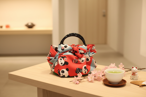 Furoshiki-Tasche „Panda“ mit rotem Panda-Motiv und schwarzen Kunststoffgriffen
